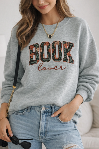 Person wearing a gray sweatshirt with 'book lover' text, standing against a neutral background.