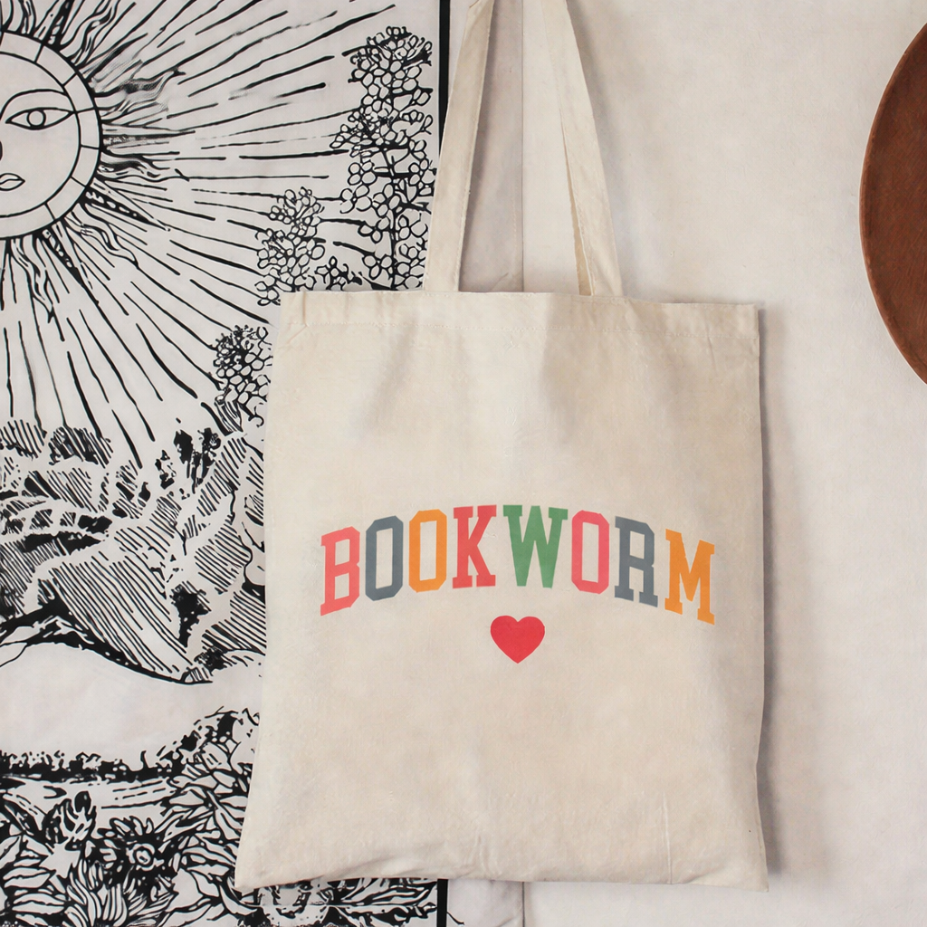 Tote bag with 'BOOKWORM' text and heart symbol on a decorative background