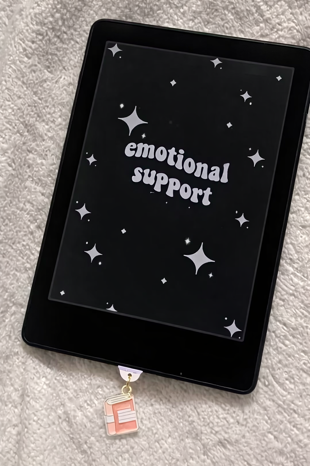 Tablet with 'emotional support' text on a starry background, held by a charm.
