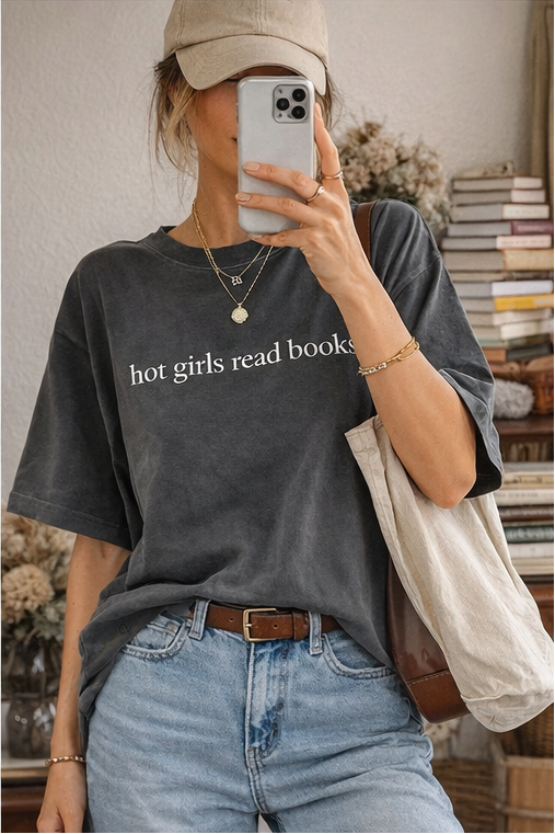 Person wearing a dark gray t-shirt with 'hot girls read books' text, holding a phone.