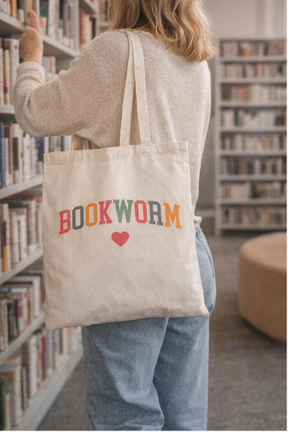 Person holding a tote bag with 'BOOKWORM' text in a library setting
